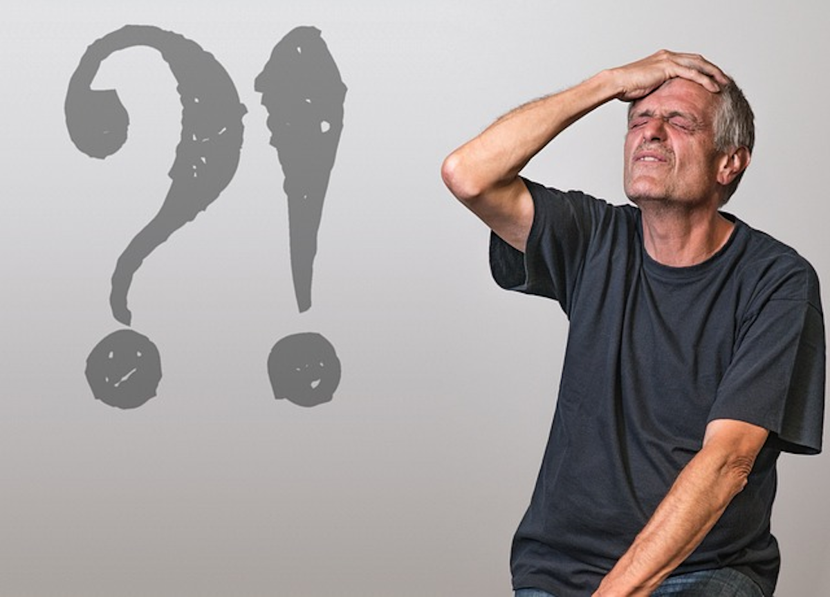 This thought-provoking image captures an elderly man with a pained expression, holding his head in apparent frustration or distress. Behind him are a question mark and exclamation mark, to suggest that he has become confused and embarrassed at having mixed up British and American English. 