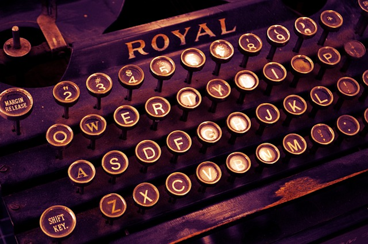 This atmospheric image presents a vintage typewriter keyboard, with illuminated keys bearing letters and symbols. The warm, dimly lit tones and the iconic "Royal" branding evoke a sense of nostalgia for the era of traditional writing instruments and craftsmanship. This refers to the dropping of letters in British vs American English. 