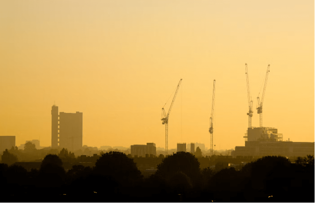 A silhouetted cityscape at sunset, with cranes and construction sites visible, representing the constantly evolving urban landscape. This accurately describes the setting of Zadie Smith’s novel, NW. 
