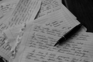 Ripped pieces of paper covered in handwriting, a black ink pen in the top right